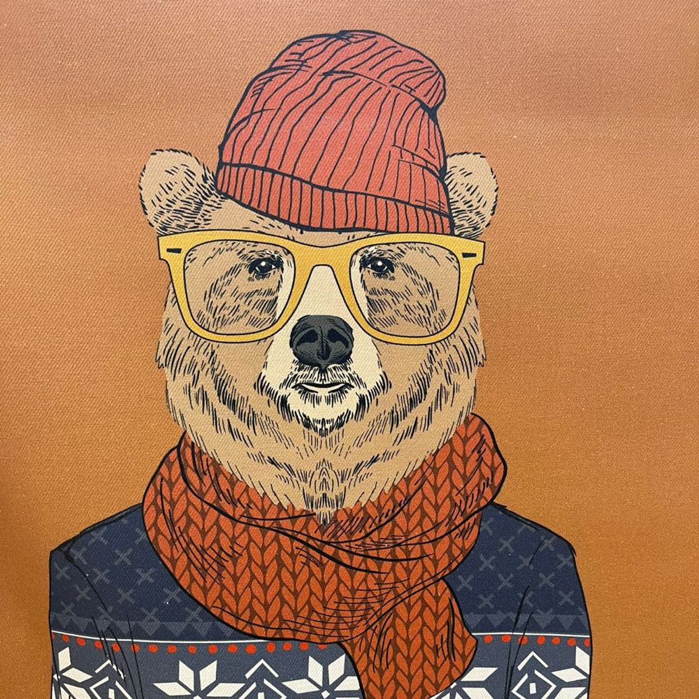 Stoff von einem stilisierten Bären mit Brille, Mütze und Schal auf einem orangefarbenen Hintergrund.