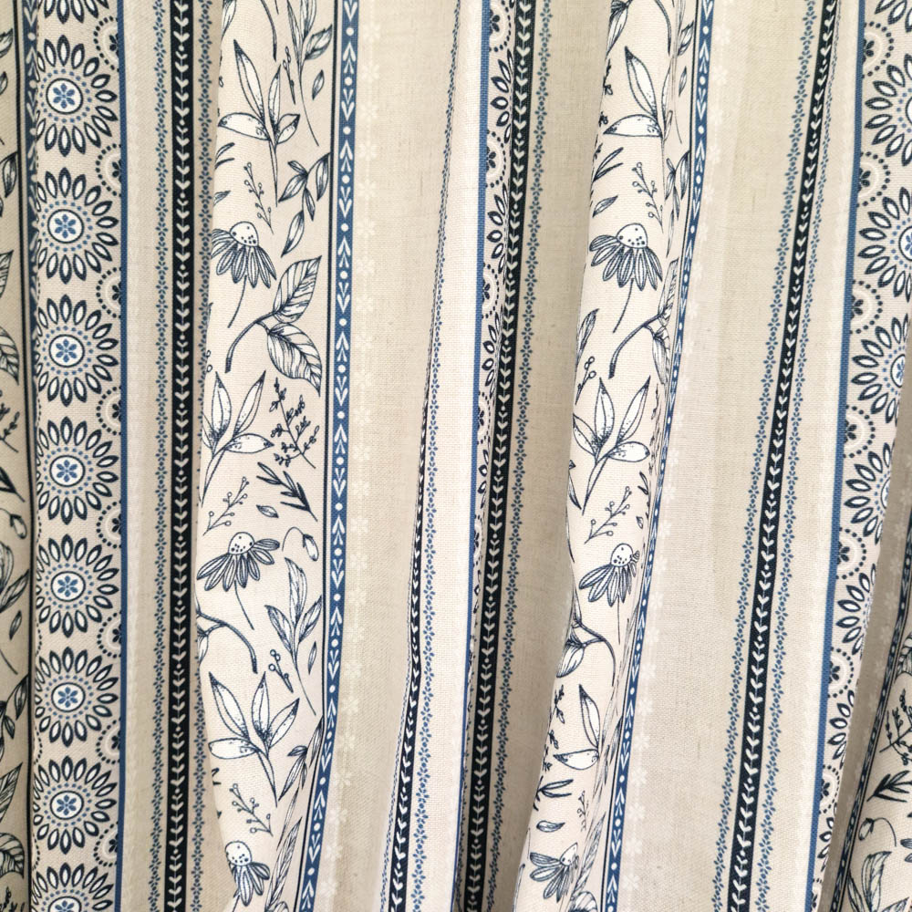 Stoff von floralen und geometrischen Mustern in Blau- und Beigetönen auf einem hellen Hintergrund.