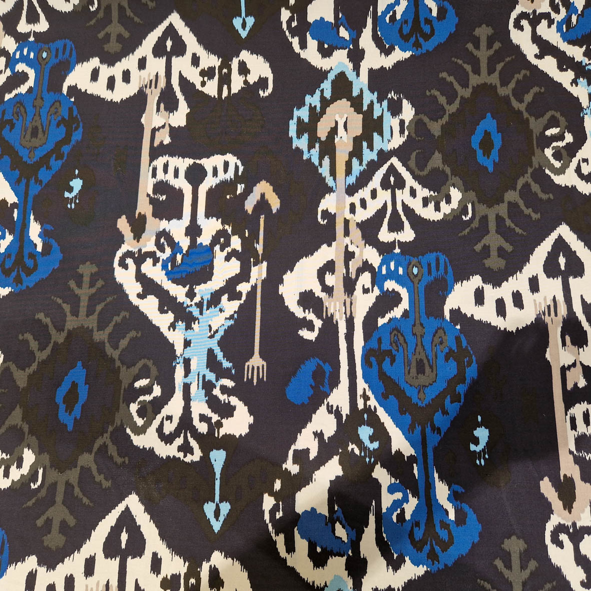 Stoff von geometrischem Muster in Blau, Weiß und Schwarz mit stilisierten Ornamenten und Pfeilen.