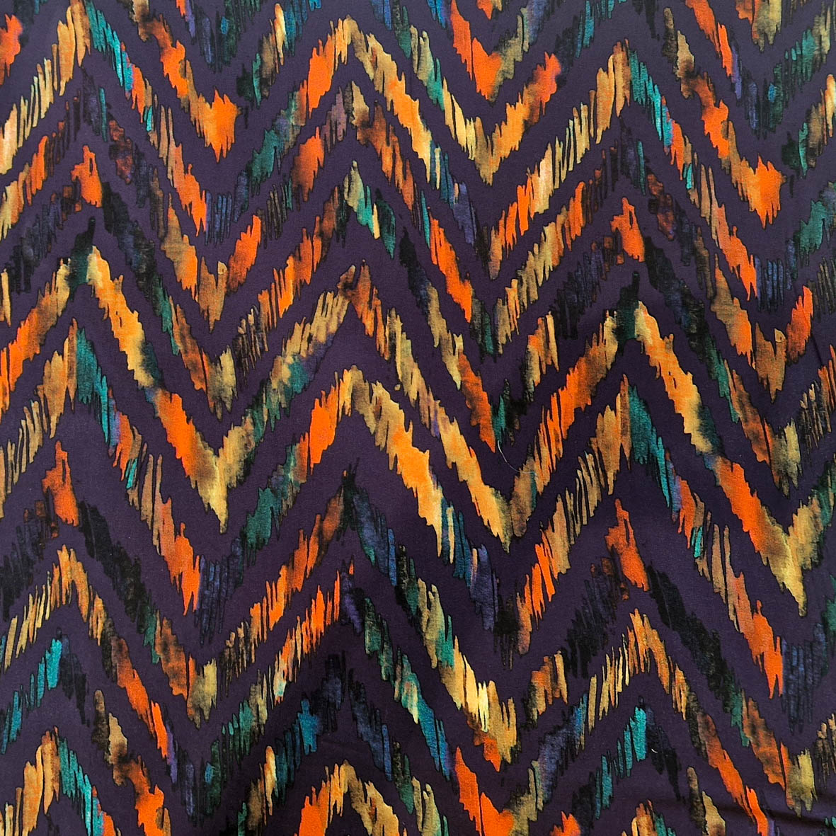 Stoff von Zickzack-Muster in Orange, Grün und Gold auf dunklem Hintergrund mit dynamischen Farbverläufen.